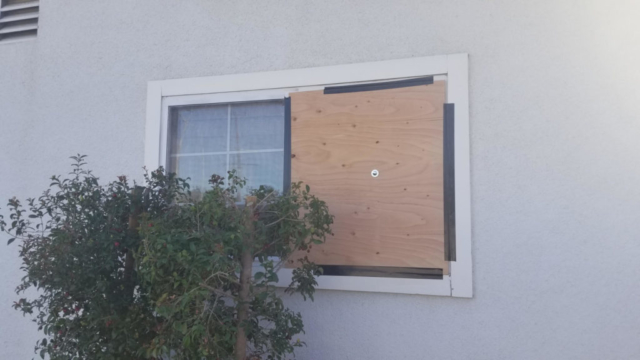 Exterior of a family living room broken window boarded up